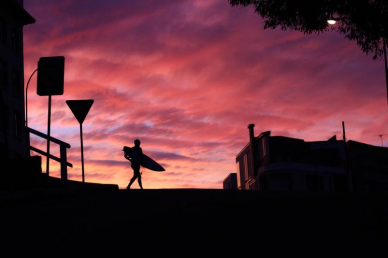 Laughing Emoji Australia - silhouette photography of man walking with a surfboard