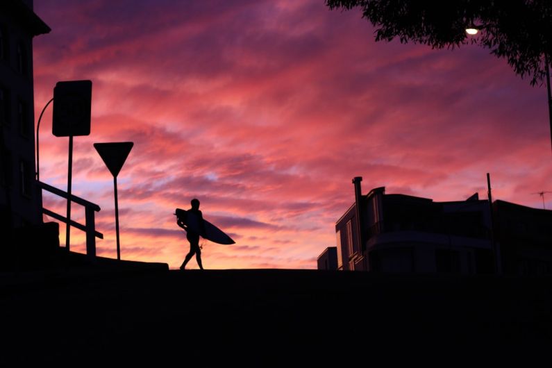 Laughing Emoji Australia - silhouette photography of man walking with a surfboard