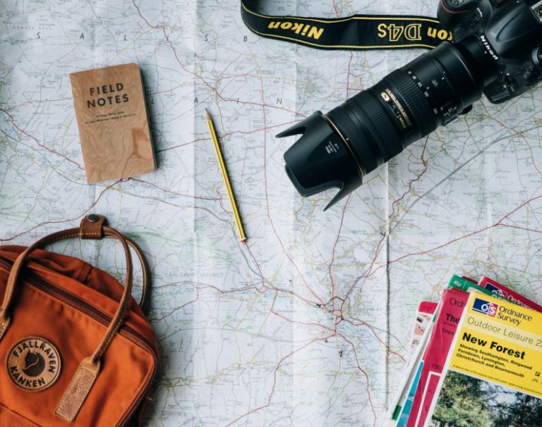 Eco Travel Australia - flat lay photography of camera, book, and bag