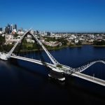 Perth Skyline Australia - an aerial view of a bridge spanning a river with a city in the background