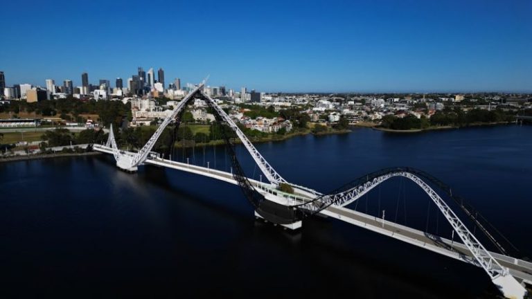 Perth Skyline Australia - an aerial view of a bridge spanning a river with a city in the background