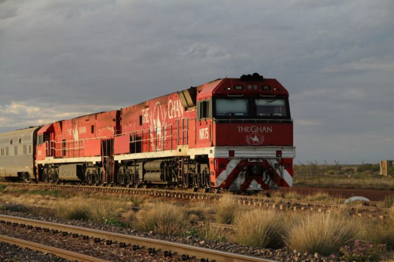 Ghan Train Australia - a red and white train traveling down train tracks