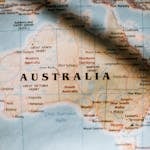 Closeup of political map of Australia with cities and regions with borders surrounded by seas and oceans placed on wall in sunny room