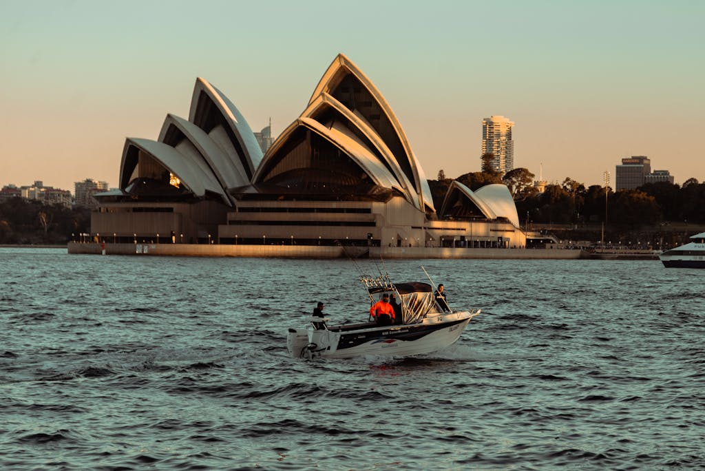 Scenic view of the Sydney Opera House during sunset with a boat navigating the harbor.