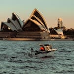 Scenic view of the Sydney Opera House during sunset with a boat navigating the harbor.