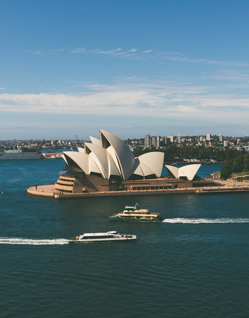Stunning aerial shot of Sydney Opera House with boats in the harbor on a sunny day.